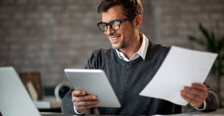 Happy businessman multi-tasking while working on new project in the office.